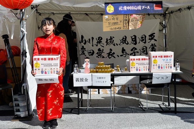 Seorang gadis Jepun yang memakai pakaian cheongsam mengumpulkan derma bagi usaha melawan wabak di China, di Tokyo, pada 2020.