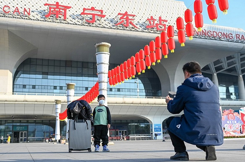 Seorang ayah mengambil gambar anaknya di depan Stesen Kereta Api Timur Nanning pada 7 Januari 2023, hari pertama musim pengangkutan TBC. (Gambar oleh Yan Lizheng dari People’s Daily Online)