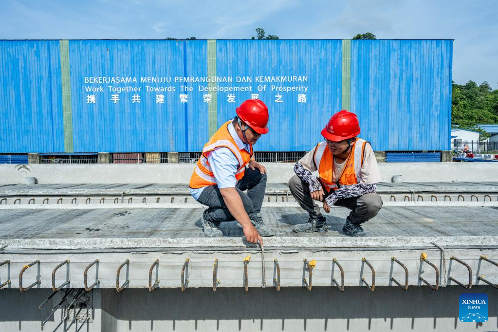 Pengarah teknikal Deng Youzhi (kanan) dan Teng De Wei, seorang jurutera muda Malaysia sedang membincangkan isu pengeluaran di pekarangan rasuk Laluan Rel Pantai Timur (ECRL), sebuah projek infrastruktur utama di bawah Inisiatif Jalur dan Laluan (BRI) di Kelantan, Malaysia, 26 April 2023. (Xinhua/Zhu Wei)