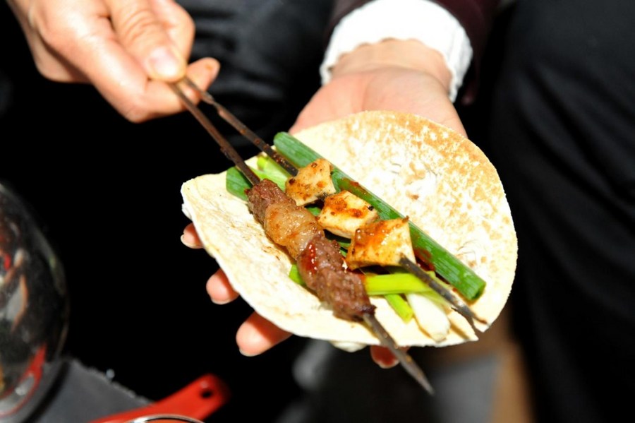 Foto yang diambil pada 11 April 2023 ini menunjukkan kuisin barbeku ala Zibo, iaitu daging dan daun bawang panggang berbalut pankek, di Zibo, provinsi Shandong, timur China. (Foto oleh Liu Yiming/Xinhua)