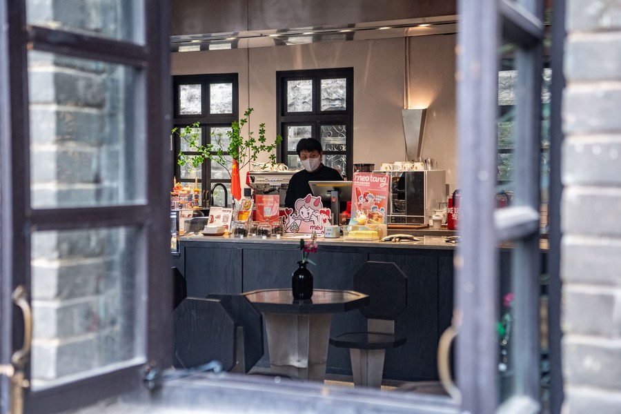 Seorang kakitangan membuat kopi di kompleks komersial yang dibina semula daripada bangunan lama di Daerah Yuzhong, Chongqing, barat daya China, 6 Okt. 2022. (Xinhua/Tang Yi)