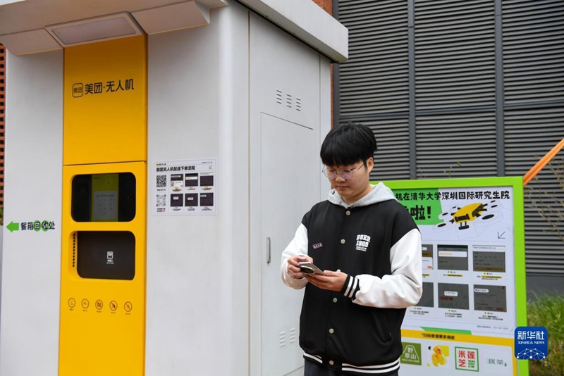 Seorang pelajar menempah makanan menggunakan dron di hab penghantaran yang terletak di kampus Sekolah Sarjana Antarabangsa Shenzhen (SIGS) Universiti Tsinghua, 19 Disember. (Xinhua/Mao Siqian)