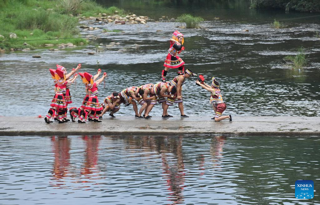 Penduduk kampung membuat persembahan di laluan batu di atas sungai di Perbandaran Wangdong di Kaunti Autonomi Rongshui Miao di Wilayah Autonomi Guangxi Zhuang, selatan China, 18 Ogos 2024. Sejak beberapa tahun mutakhir, Perbandaran Wangdong telah memanfaatkan sumber airnya yang banyak untuk menggalakkan daya hidup luar bandar. Disokong oleh "bantuan berpasangan" dari Bandar Lianjiang di Provinsi Guangdong, perbandaran itu berjaya menganjurkan pertandingan sukan air, nyanyian duet lagu gunung dan aktiviti bertemakan warisan budaya tidak ketara di sekolah. Inisiatif ini bertujuan untuk membina jenama "budaya air" dan memajukan pembangunan pelancongan budaya etnik. (Xinhua/Huang Xiaobang)